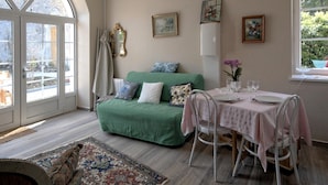 Una habitación acogedora con un sofá verde, una mesa de comedor con sillas y un ventanal grande.