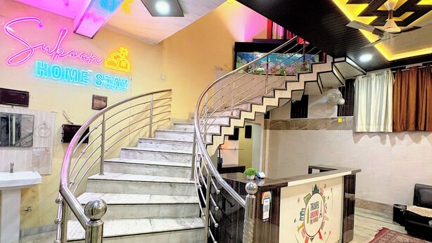 A hotel lobby with a marble staircase, a reception desk, and a neon sign. - sukoon homestay (Agra)