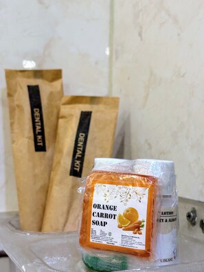 Un baño con un lavabo, un espejo y dos bolsas de papel marrones con la etiqueta 'Dental Kit' al fondo.