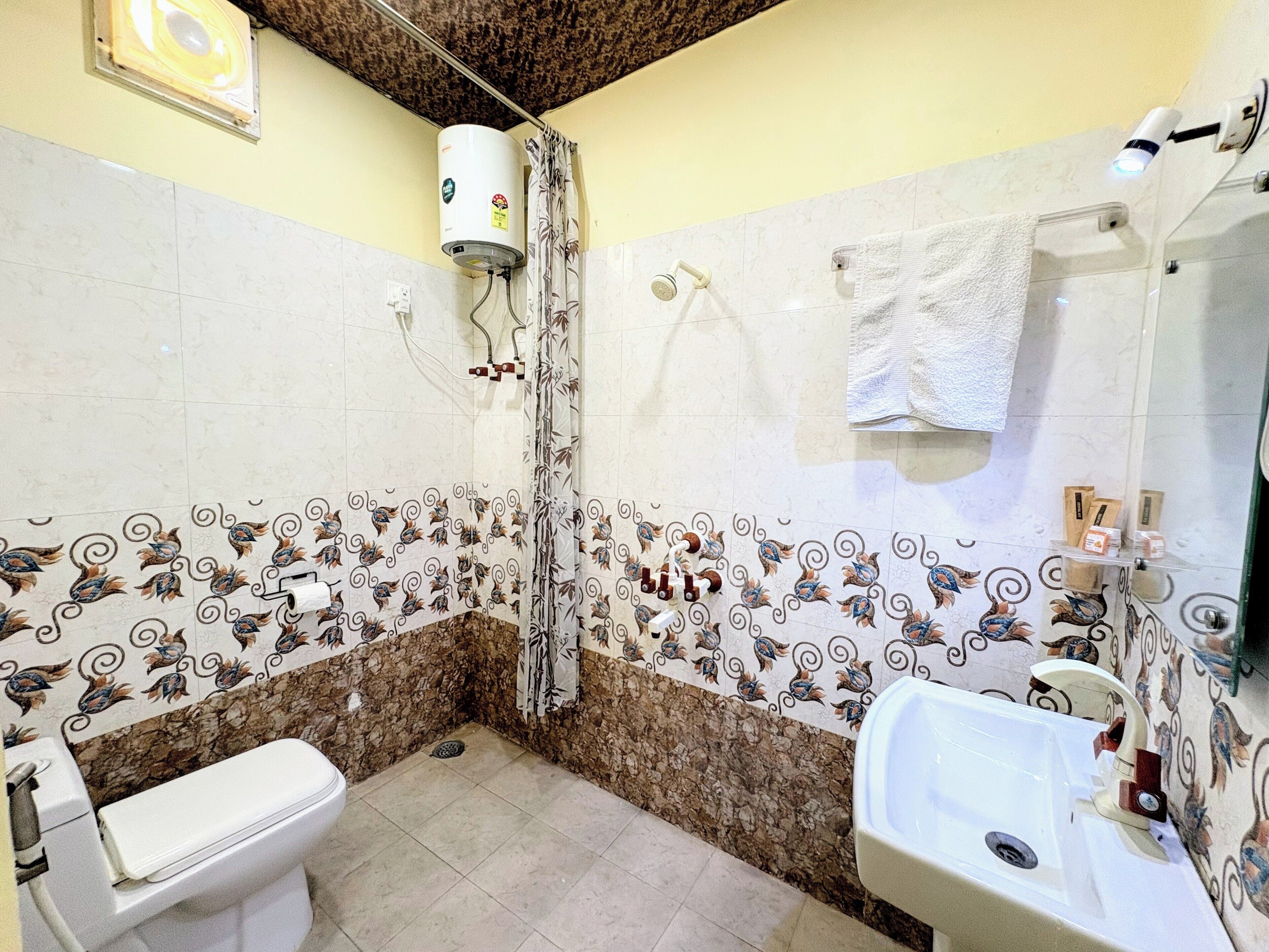 A bathroom with a toilet, sink, shower, and decorative tiled walls.