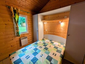 A wooden-paneled room with a bed, a window, and a door.