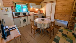 Une cuisine compacte équipée d’un lave-linge, d’un four à micro-ondes et d’une table avec des chaises.