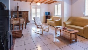 Una sala de estar con sofá, sillones, una mesa de centro de madera, televisión y chimenea.