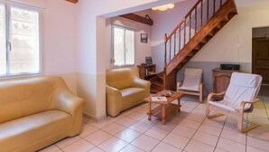 Una sala de estar con escalera de madera, sofás de cuero y una mesa de centro de madera.