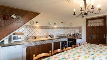 Eine Küche mit Mikrowelle, Toaster und Kaffeemaschine auf der Arbeitsplatte, einem Holzkasten und einer Chandelier.
