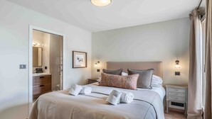 Una camera da letto con un letto, comodini, uno specchio e una porta che dà su un bagno.