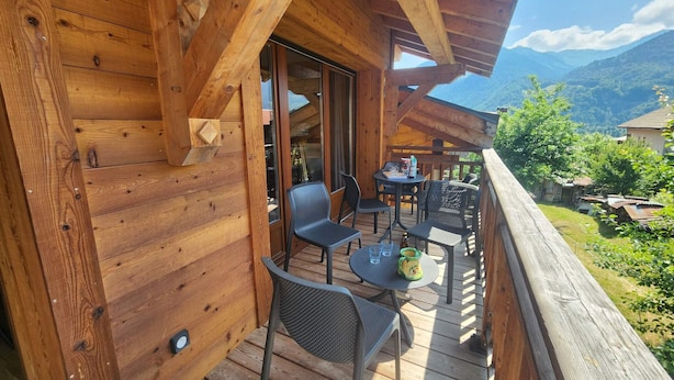 A wooden deck with outdoor seating and a view of a mountainous landscape.