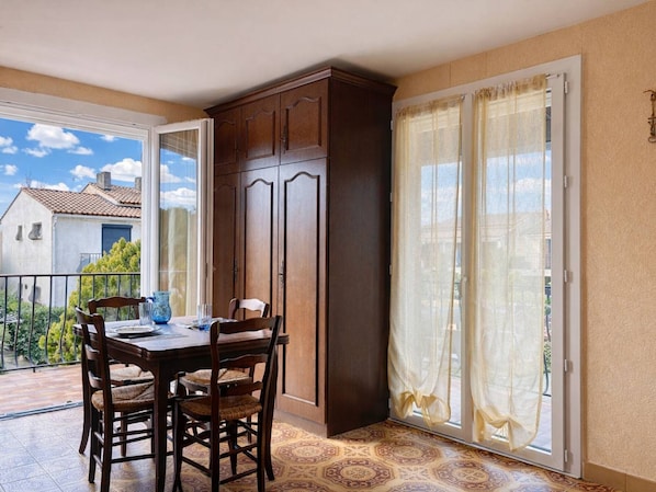 A dining area with a table and chairs, a cabinet, and a sliding glass door to a balcony.