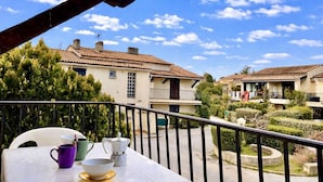 A balcony with a table, chairs, and a view of terraced houses. - Studio rental, steps from the beach with parking - La Londe-les-Maures (La Londe-les-Maures)