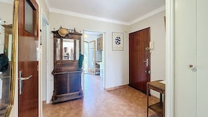 Un couloir avec une porte en bois, un miroir et un tableau encadré accroché au mur.