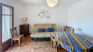 Une chambre à coucher avec un lit, une chaise, une petite table et une fenêtre.