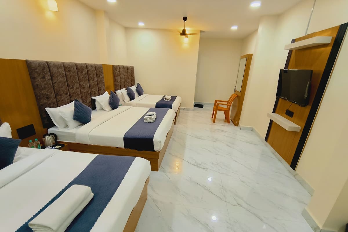 A hotel room with two beds, a TV, a ceiling fan, and a wooden door.