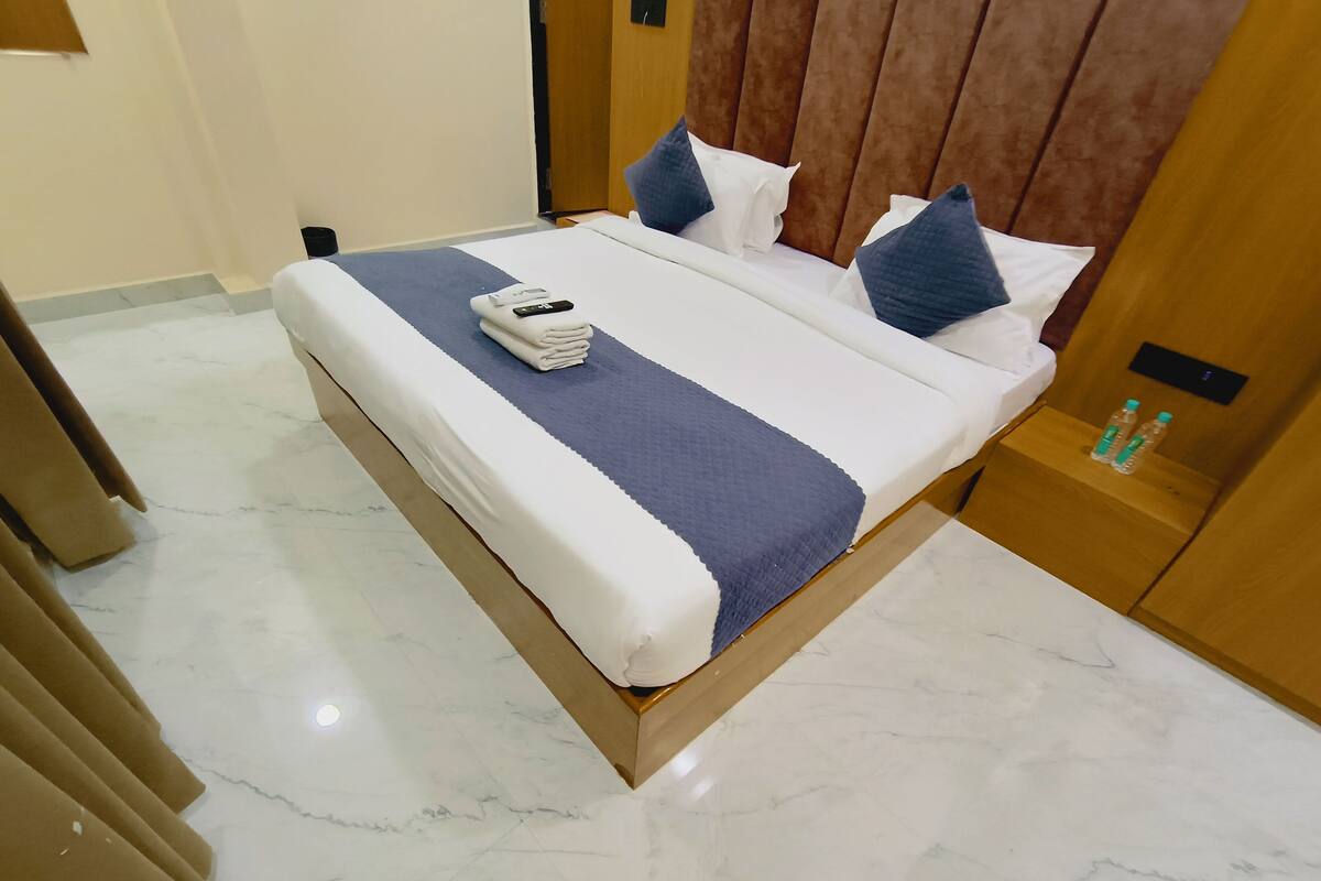 A hotel room with a bed, a nightstand, a wooden headboard, and a marble floor.