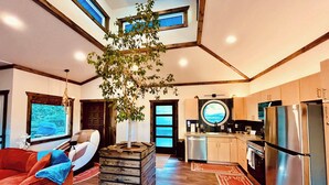 A modern kitchen with a built-in island, a large window, and a view of the outdoors. - Tranquil Hideaway | Romantic Spa Retreat with Hot Tub, Cold Plunge and Sauna (Denniston)