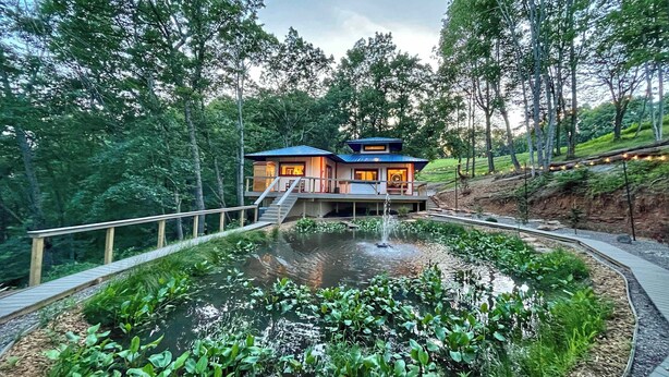 A house with a pond, surrounded by trees, and a wooden deck. - Tranquil Hideaway | Romantic Spa Retreat with Hot Tub, Cold Plunge and Sauna (Denniston)