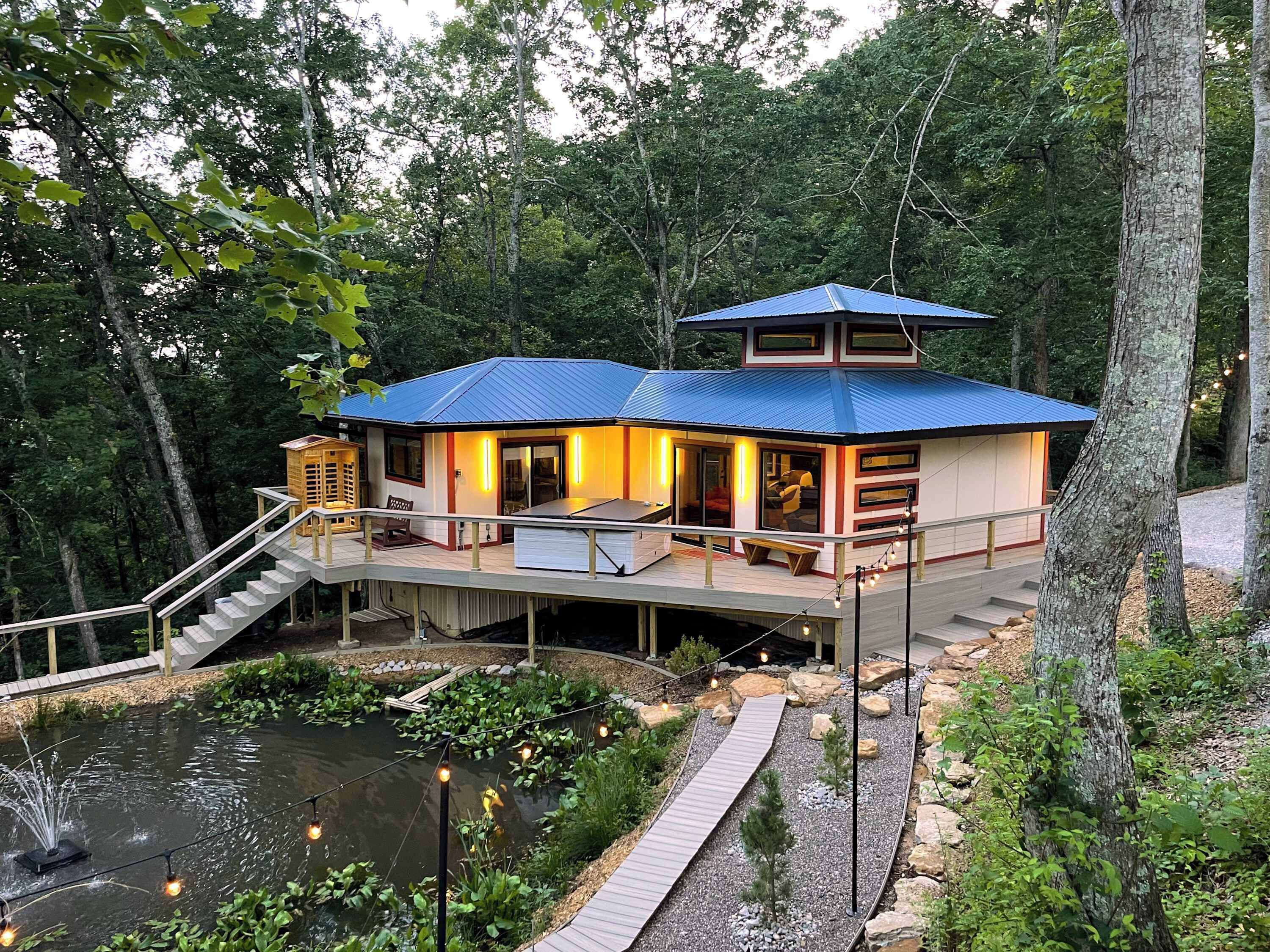 Una casa con techo azul, un balcón y un estanque.