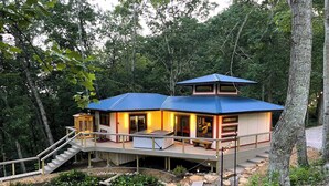 A house with a blue roof, a deck, and a pond. - Tranquil Hideaway | Romantic Spa Retreat with Hot Tub, Cold Plunge and Sauna (Denniston)