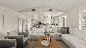 A spacious living room with a large sectional sofa, a coffee table, and a kitchen in the background.