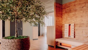 Un interior modern amb una paret de fusta, un arbre gran en test i una banca amb calefacció integrada.
