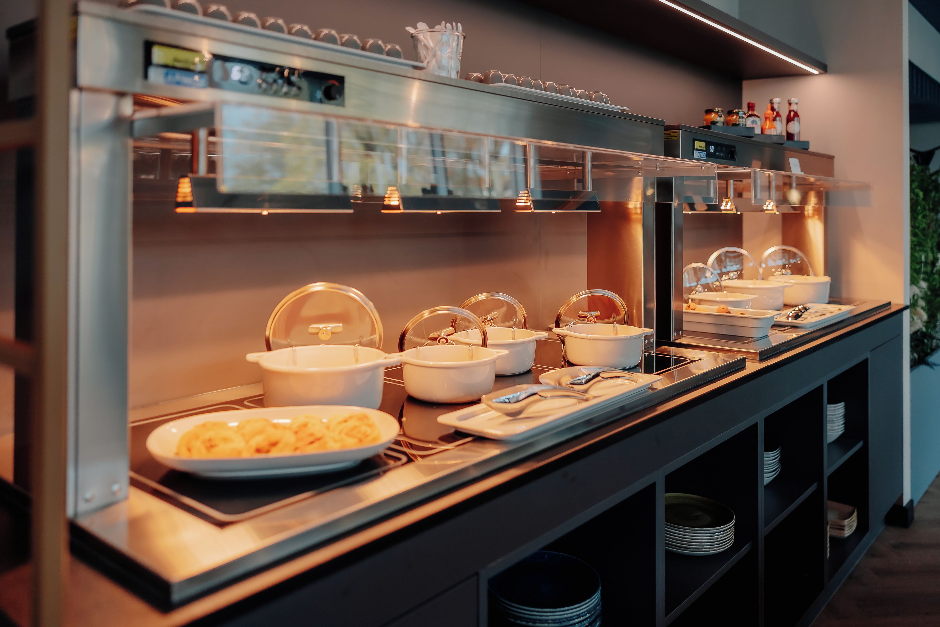 A buffet setup with various food containers and utensils.