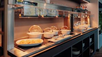 A buffet setup with various food containers and utensils.