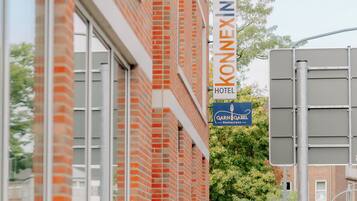 A hotel with a brick facade and a sign for 'Konex Inn Hotel' and 'Garn & Gabel Restaurant'.