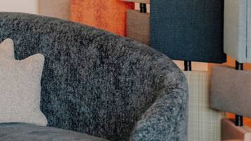 Parte de un hotel con varios paneles de pared de tela y un sofá tapizado gris con un cojín.