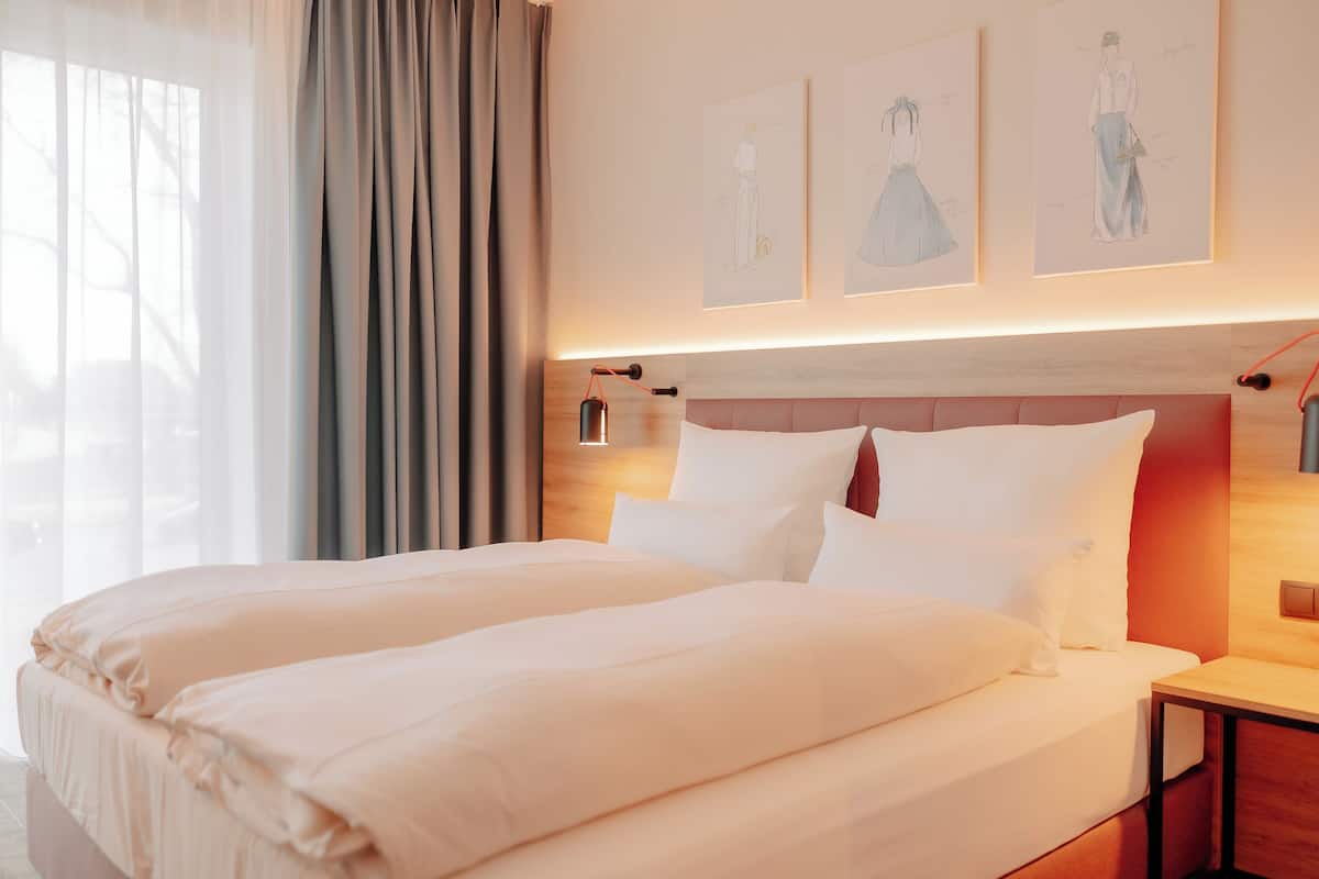 A hotel room with a large bed, a wooden headboard, and artwork on the wall.