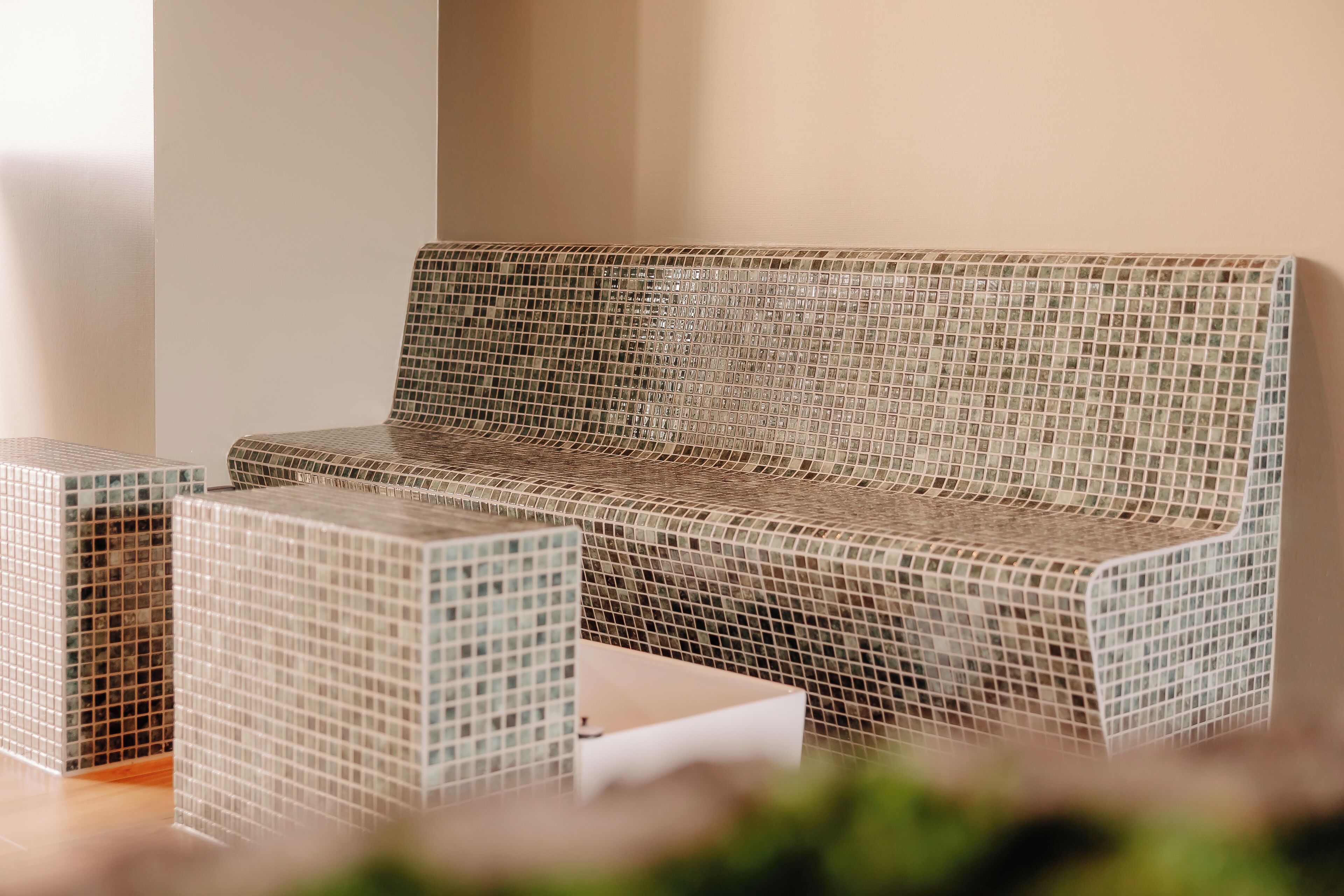 A mosaic-tiled sofa with a matching side table, set against a plain wall.