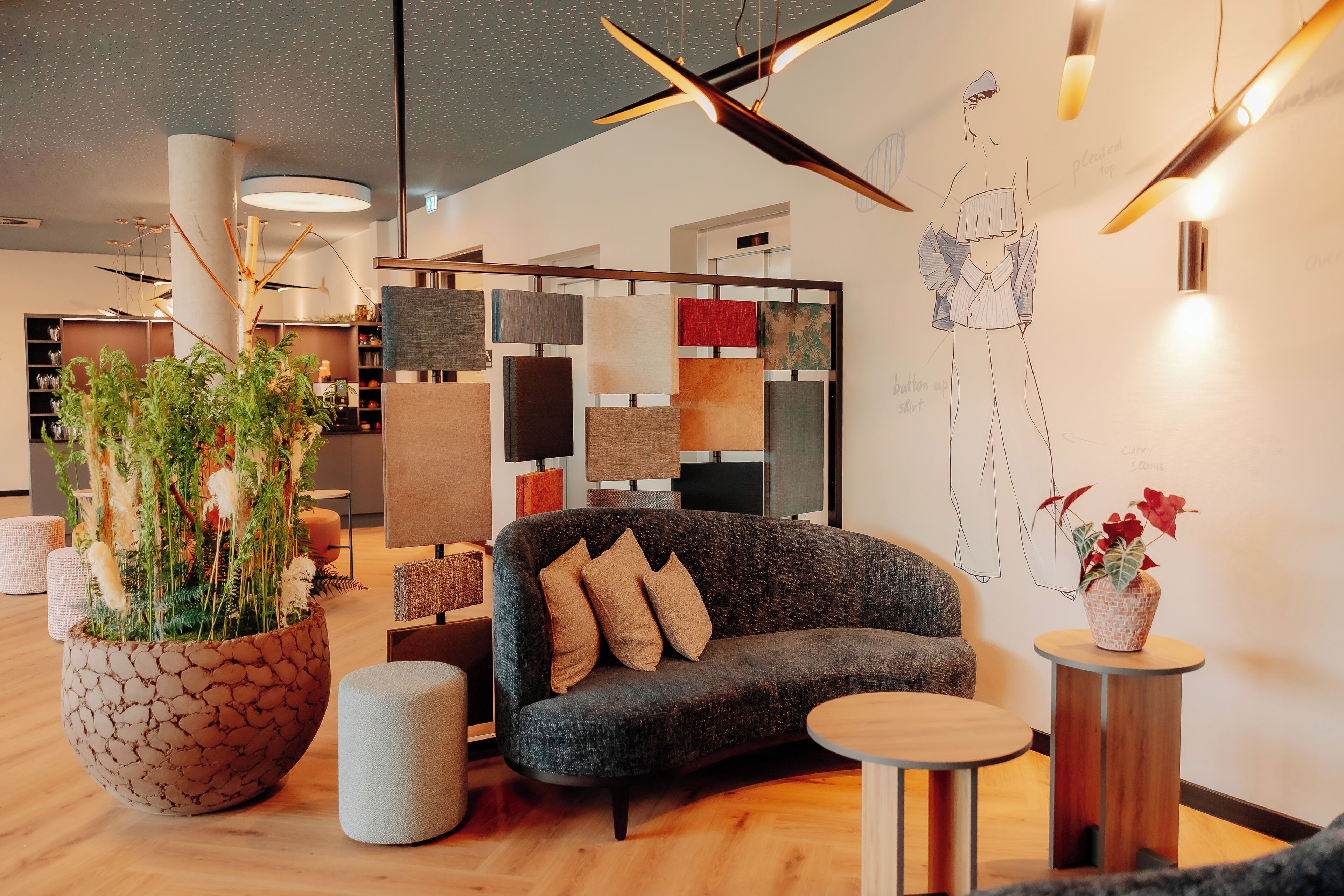 Un interior moderno con un sofá gris, una mesa redonda de madera y una gran planta en maceta.