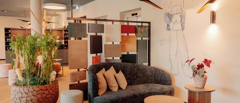 A modern interior with a grey sofa, a round wooden table, and a large potted plant.