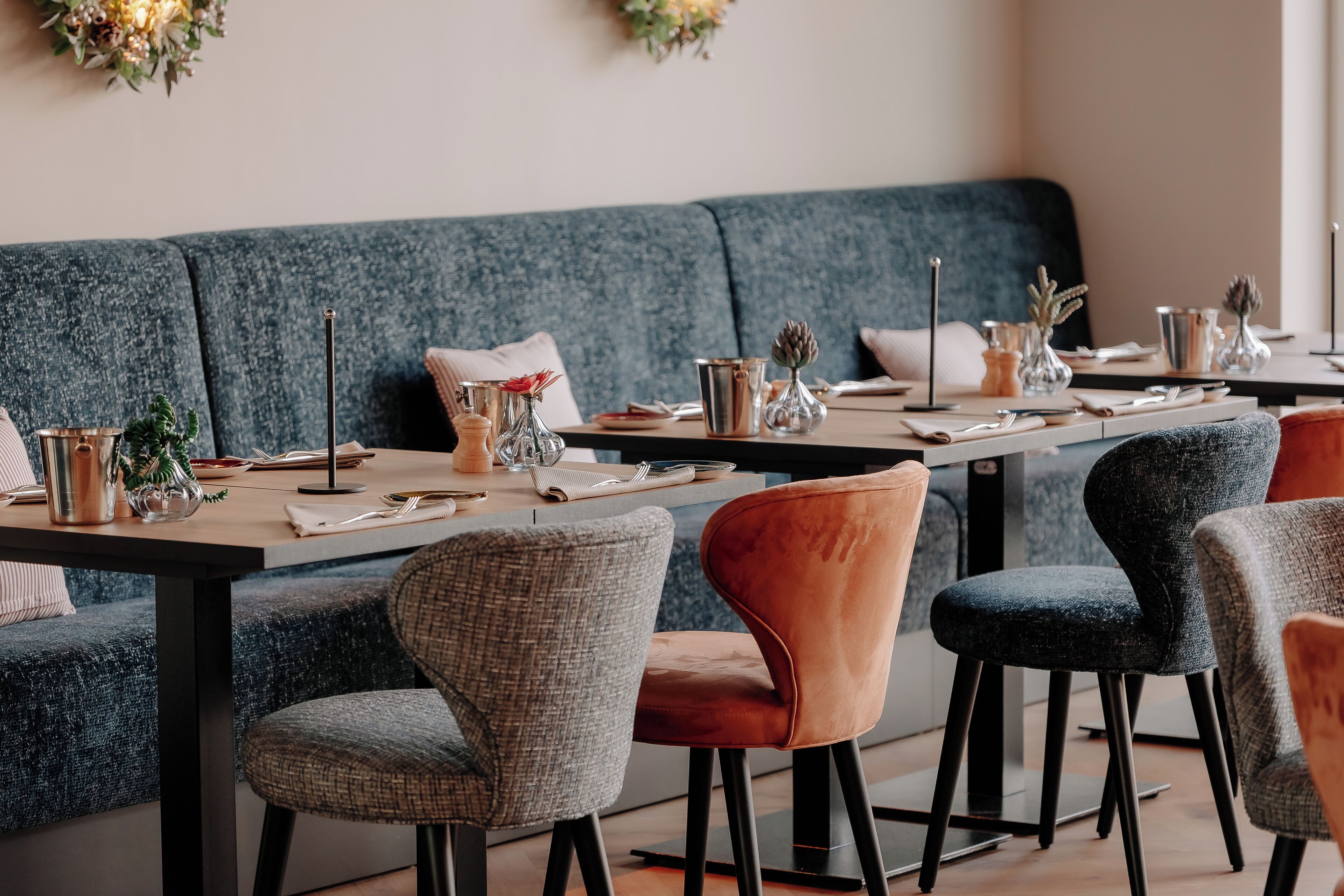 Un comedor con una mesa larga dispuesta para cuatro personas, rodeada de sillas tapizadas.