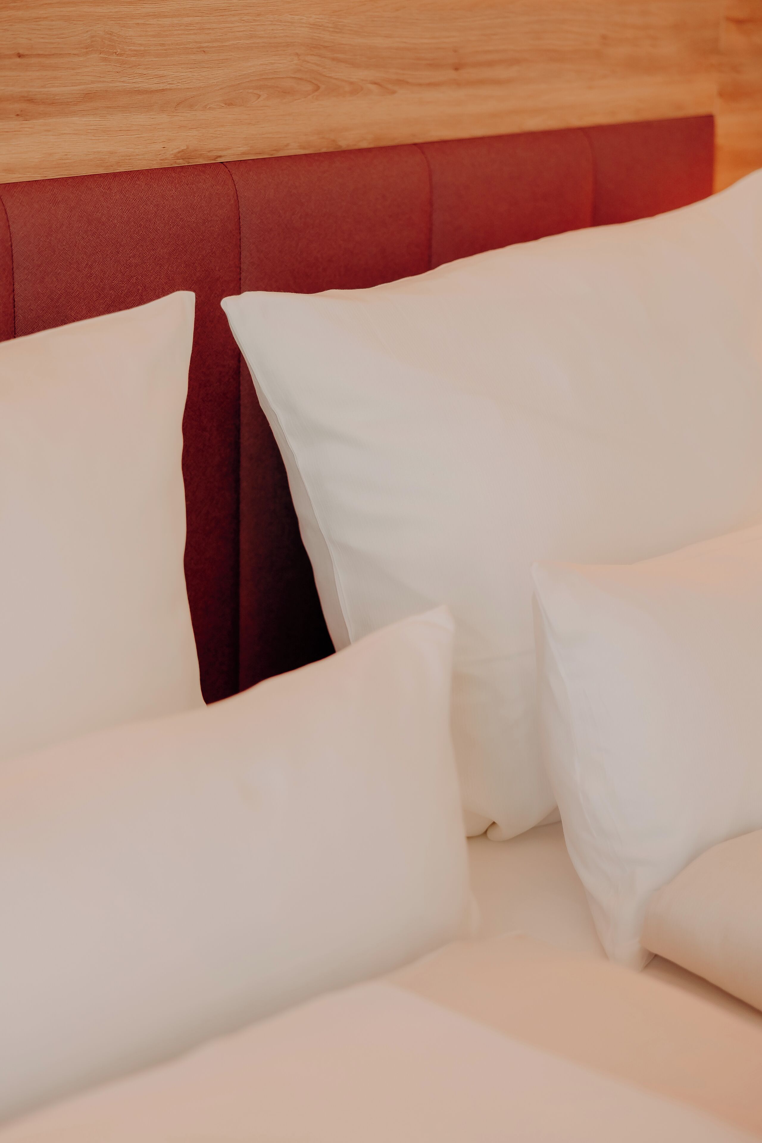 A bed with white pillows and a red headboard.