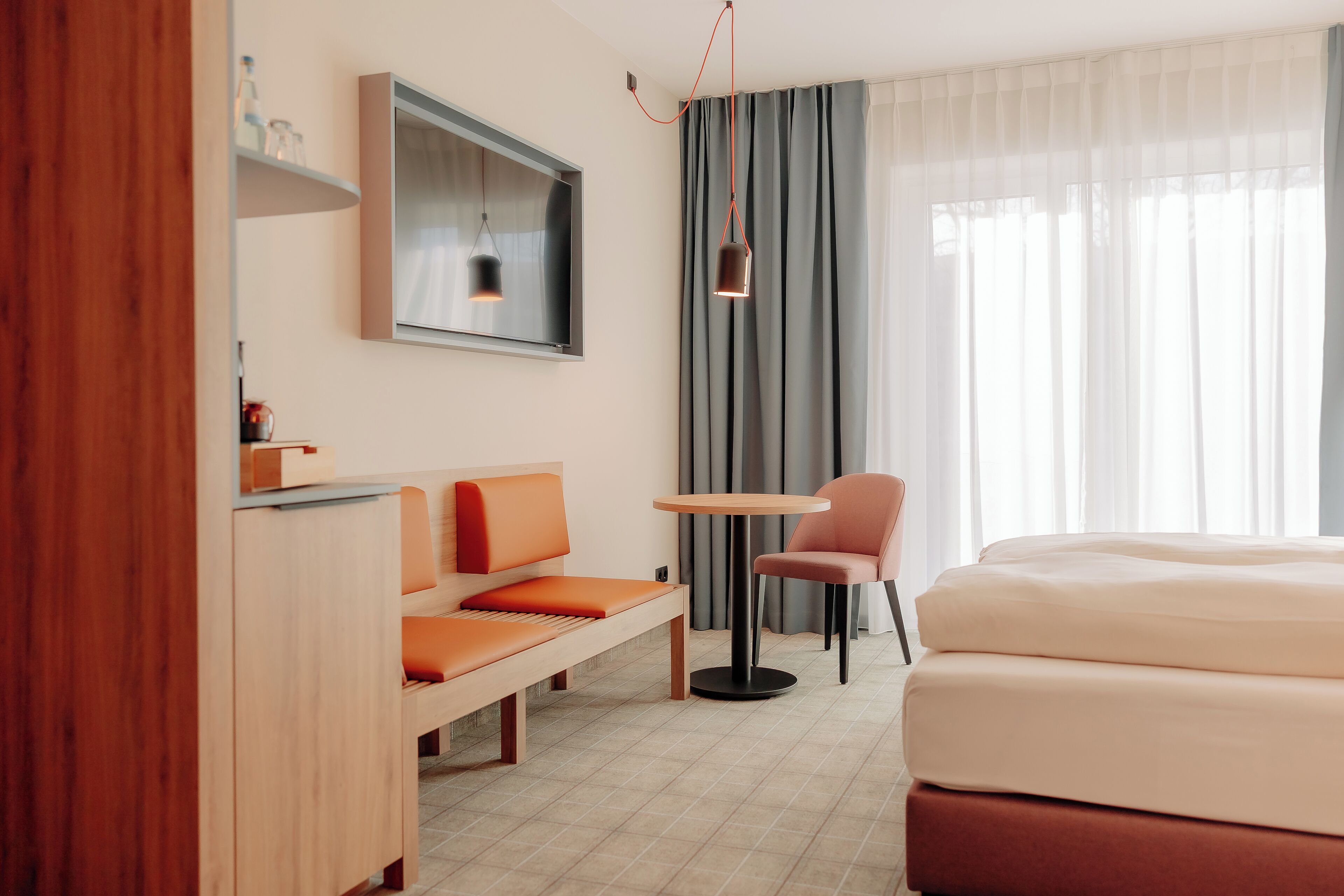 A modern hotel room with a bed, a sofa, a small table, and a chair.