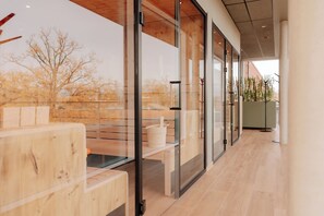 A modern interior with glass partitions, wooden furniture, and a view of trees outside. - KONNEX INN Nordhorn by Hackmann (Nordhorn)