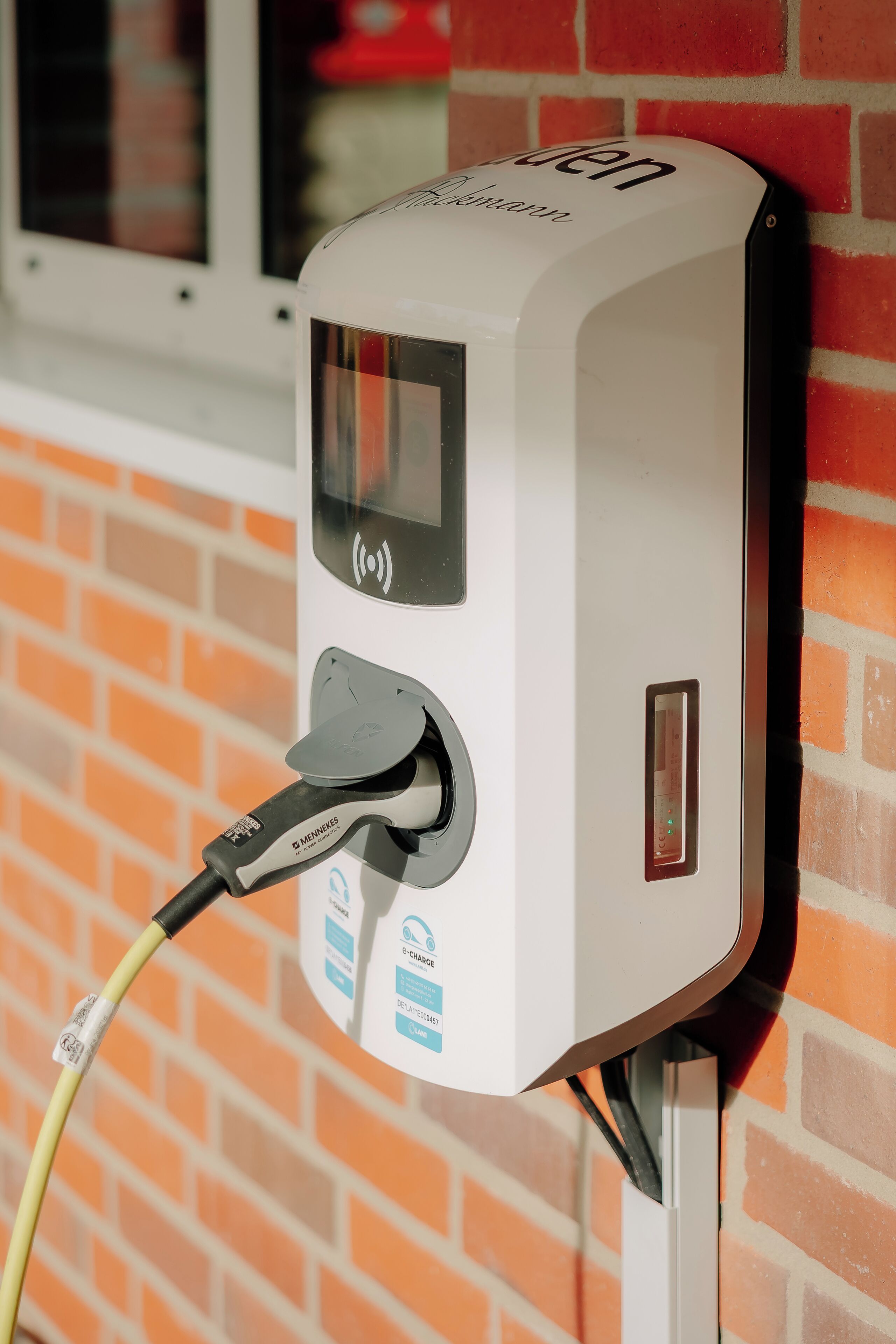 An electric vehicle charging station mounted on a brick wall.