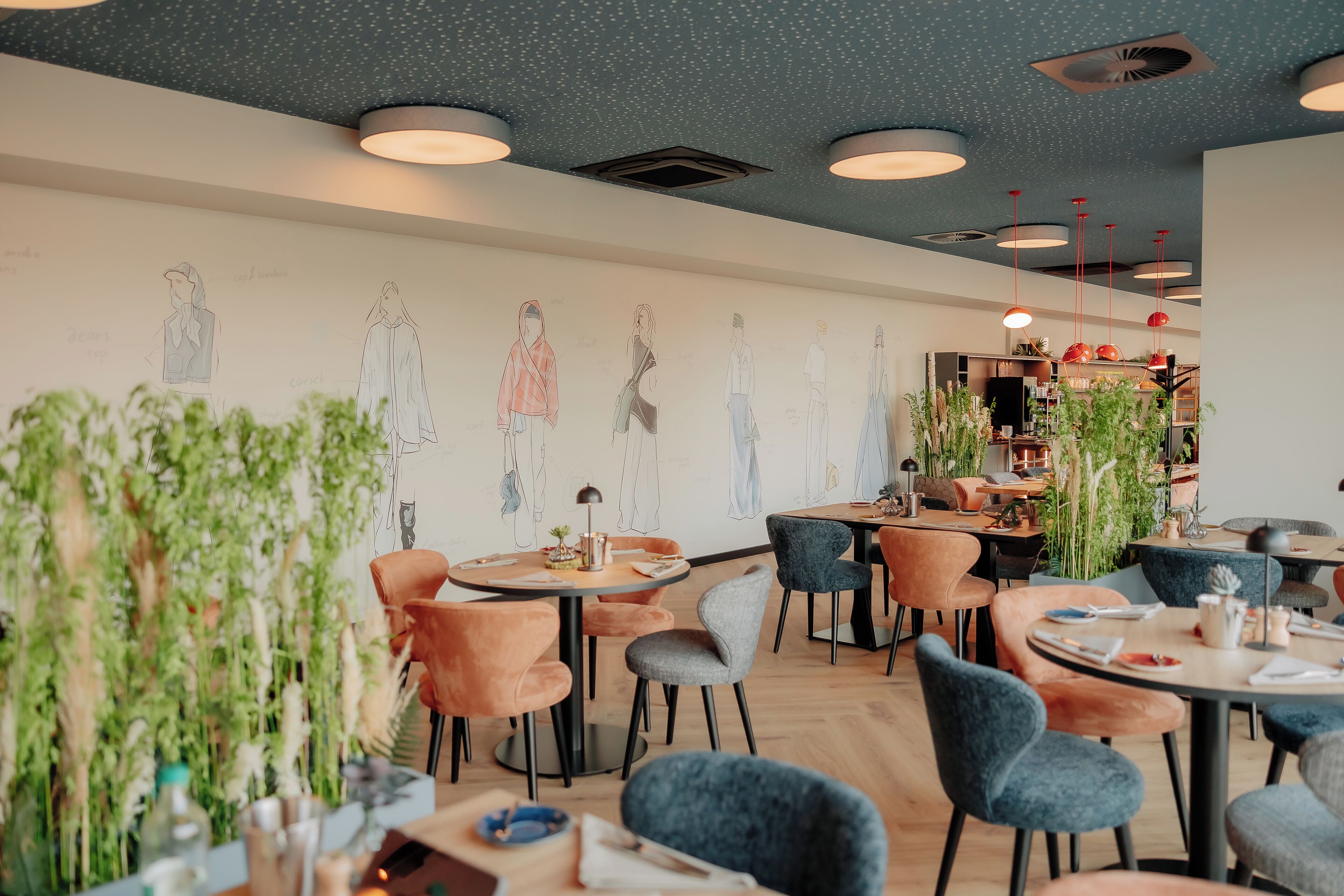 Interior moderno de restaurante con mesas redondas, sillas y un mural en la pared.