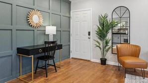 A room with a desk, chair, and a potted plant.
