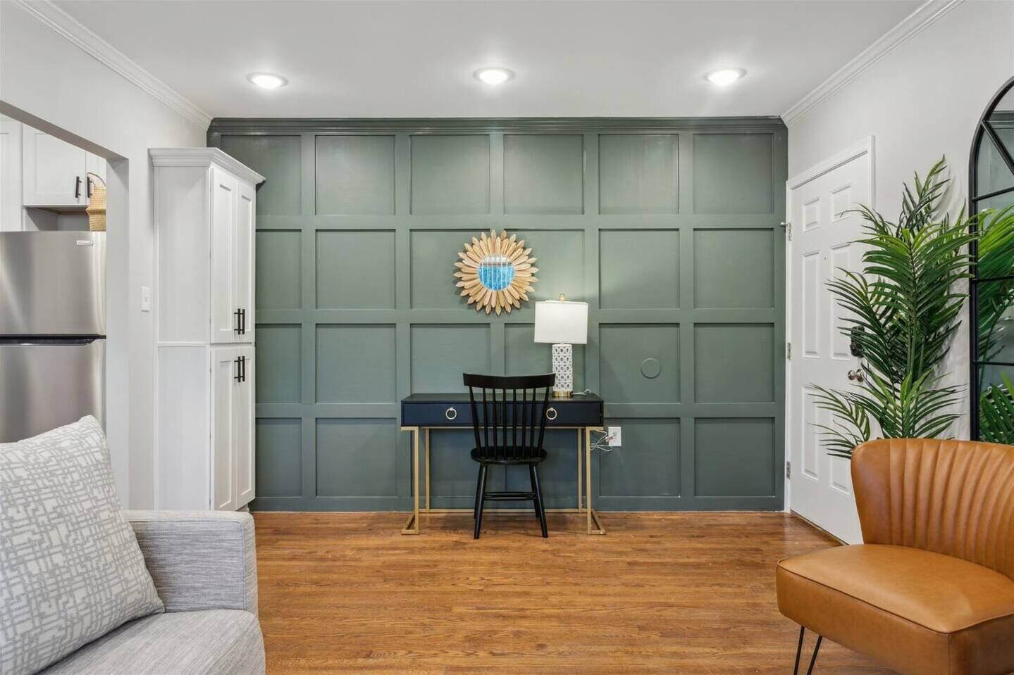 A room with a desk, chair, and a large plant.