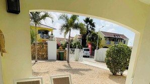 An outdoor dining area with a table and chairs, a view of the street, and a building in the background. - Villa 1A Relax & Dive Resort Bonaire Village (Kralendijk)