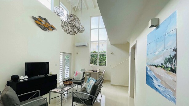 A spacious living area with a flat-screen TV, modern furniture, and a large window. - Villa 1A Relax & Dive Resort Bonaire Village (Kralendijk)