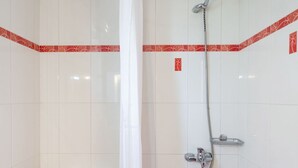 Et badeværelse med bruser, toilet og badekar.