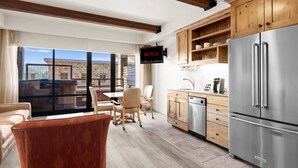 Una cocina moderna con armarios de madera, un refrigerador de acero inoxidable y un comedor con vistas.