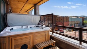 Un jacuzzi con bancos de madera en un balcón con vista a la calle.