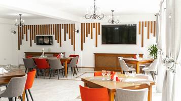 Un comedor moderno con una mesa de madera, sillas y un televisor montado en la pared.