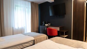 A hotel room with two beds, a desk with a chair, a TV mounted on the wall, and a wardrobe.