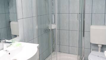 A bathroom with a glass-enclosed shower, a white sink, and a toilet.