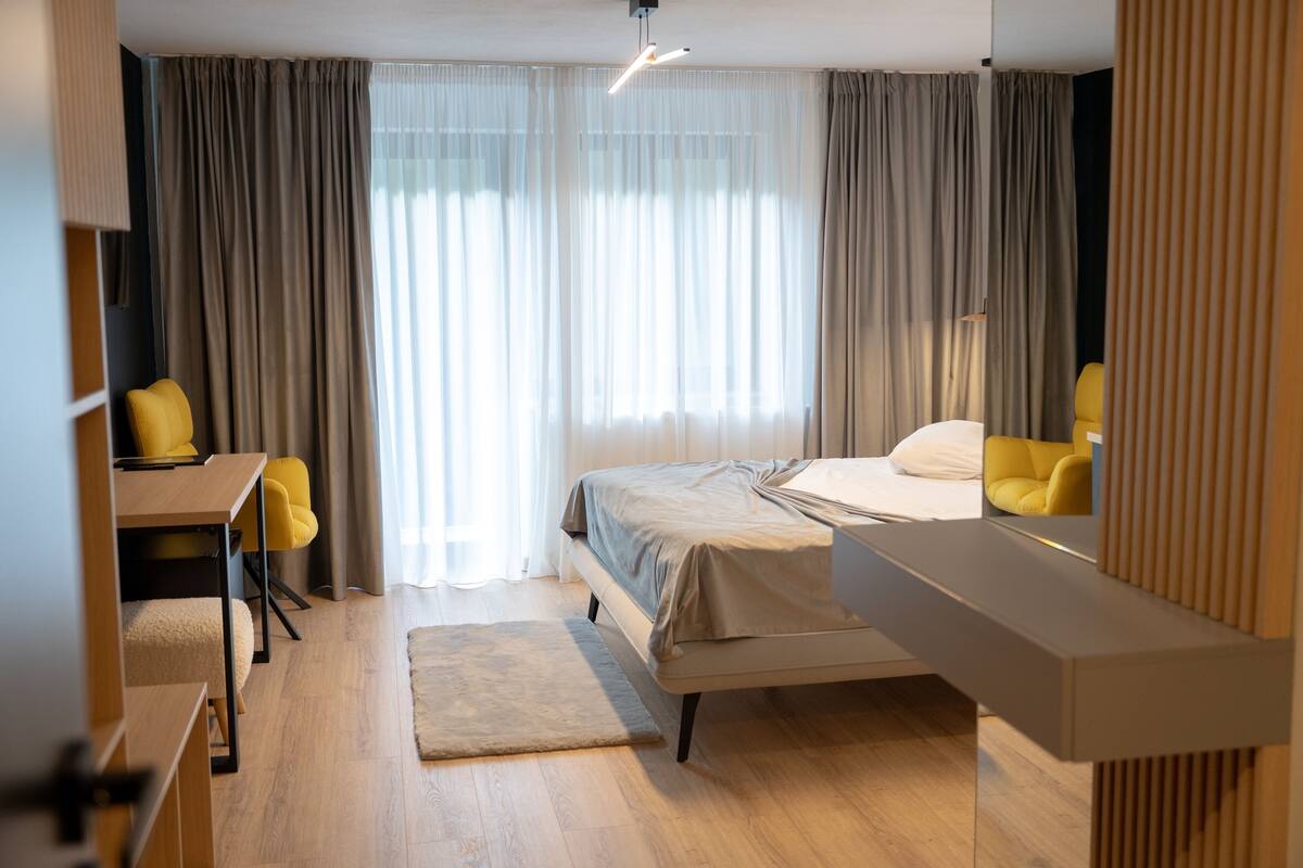 A modern hotel room with a bed, a desk, and a chair.