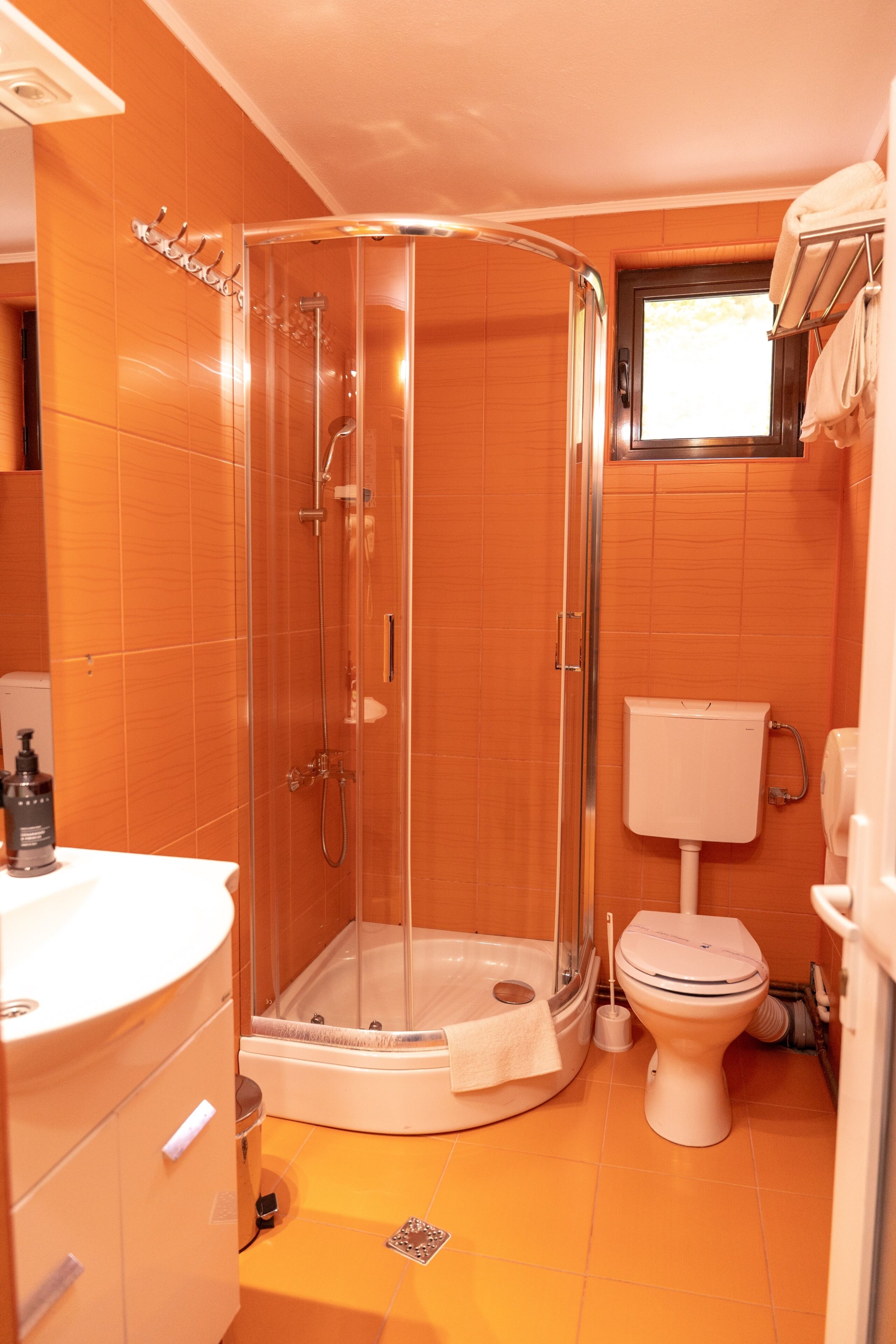 A bathroom with a glass-enclosed shower, a toilet, and a sink.