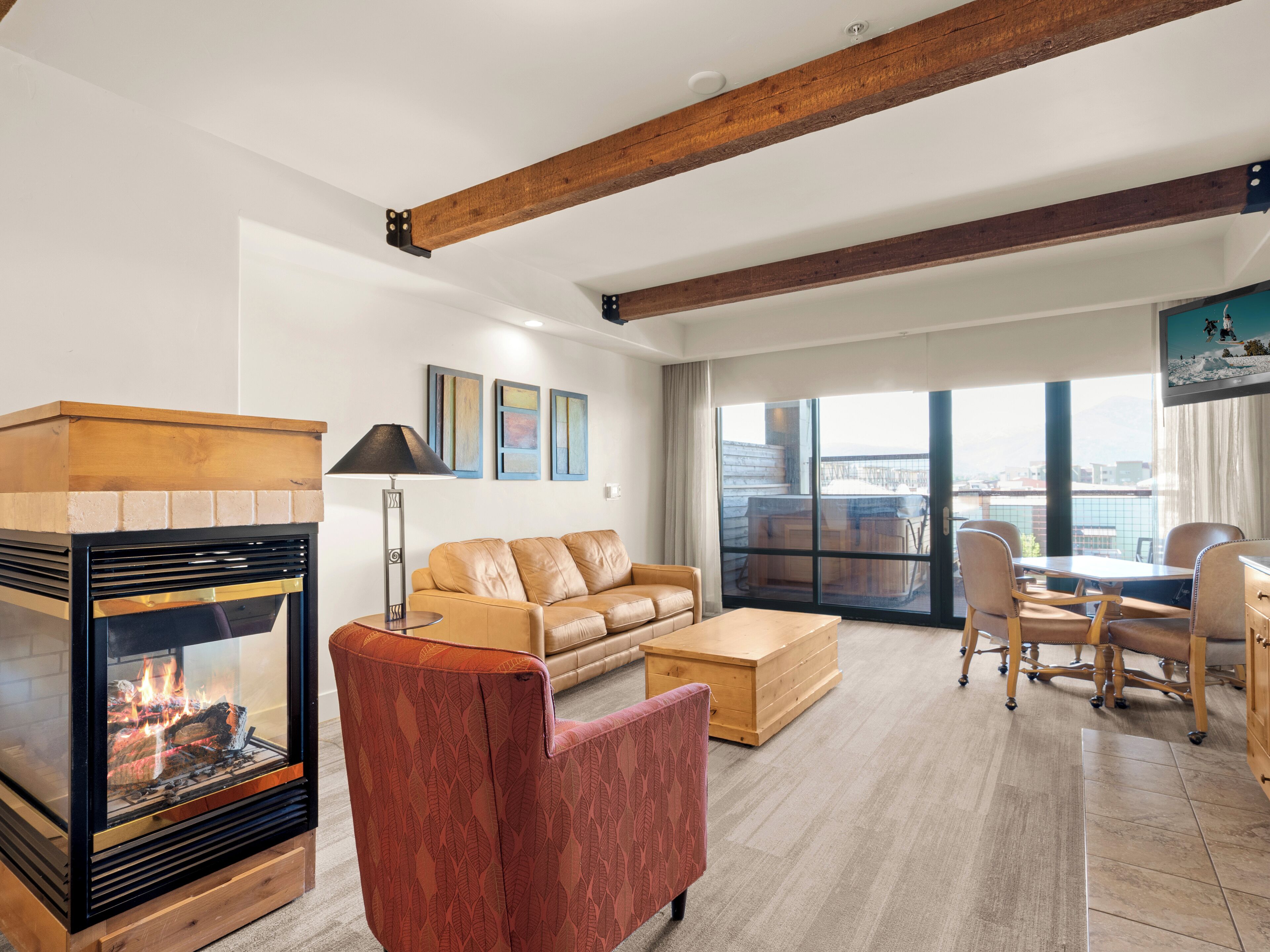 A spacious living room with a fireplace, a sofa, a coffee table, and a dining area with chairs.